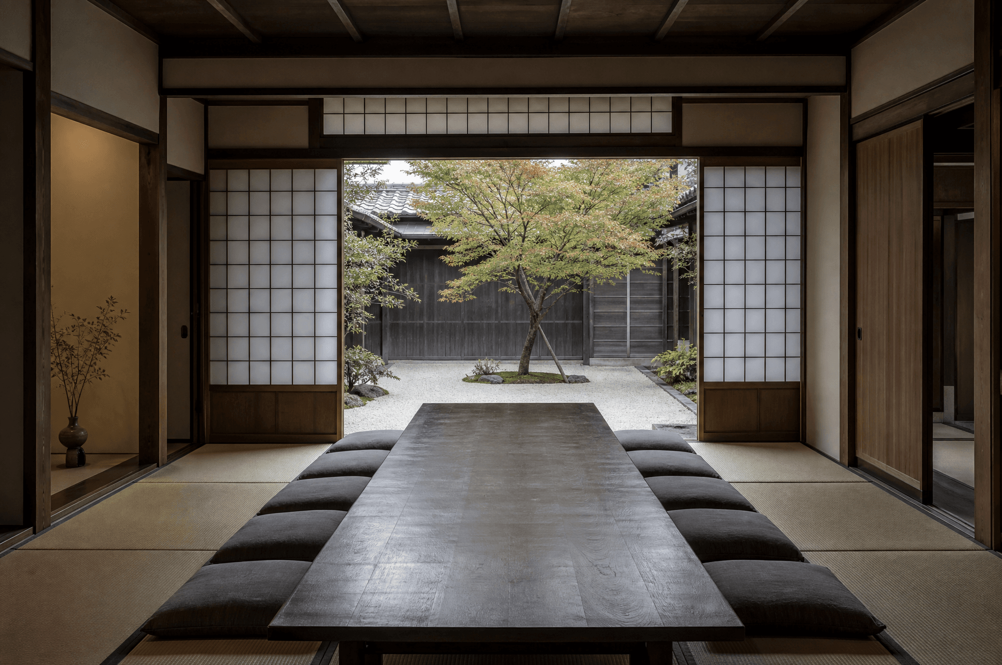 A Kyoto machiya room with shoji screens open to a gravel courtyard and a single maple.